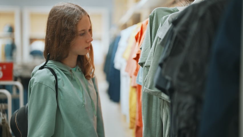 Teenage girl choosing clothes in mall.