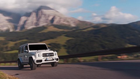 Alpe di Siusi, Dolomites-09.10.2021: Cinematic rolling shot of Mercedes Benz G Class SUV luxury sport car driving on a mountain highway in Alpe di Siusi, Dolomites Mountain Alps, Italy 