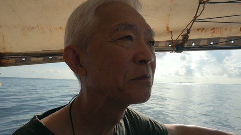 Asian senior man on Phuket Thailand longtail boat vacation travel to the sea
