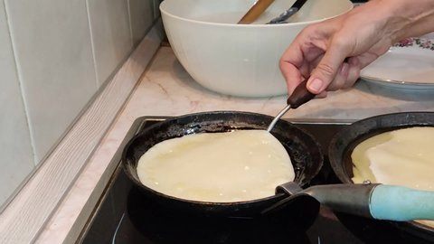 Cooking pancakes. Traditional russian blin on a cast-iron frying pan. Maslenitsa is an Eastern Slavic traditional holiday, celebrated during the week before the Great Lent.