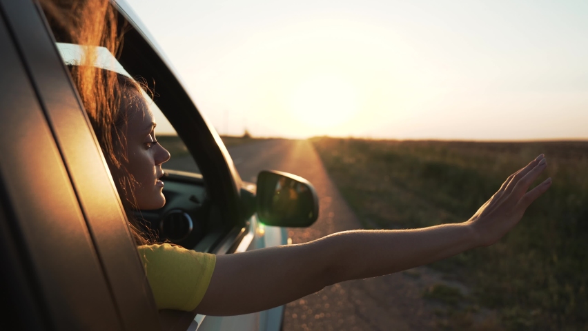 Child in car window. Family car trip. Child hair in wind. Girl looks out of car window. Happy child travel with his family. Girl stretches out his hand to wind. Happy family travel concept by car | Shutterstock HD Video #1085719250