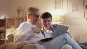 Father son leisure. Family together. Bonding relationship. Senior dad browsing internet on laptop with teen offspring on couch at home living room. - Powered by Shutterstock - Get 15% off with code: PIKWIZARD15