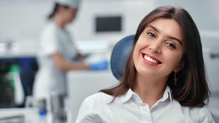 Closeup smiling beautiful brunette young woman sitting dentistry chair with positive emotion. Portrait happy female patient visit stomatology for regular teeth mouth cavity checkup at medical clinic Royalty-Free Stock Footage #1085722670