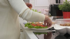Woman cooking festive dinner in the kitchen making delicious canape topped with red caviar. Traditional russian Christmas and New Year appetizer. High quality 4k footage