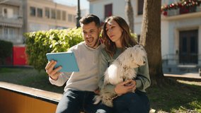 Young couple holding dog having video call at park