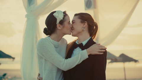 Portrait of a Happy Just Married Beautiful Lesbian Couple Kissing, Showing Off Their Gold Wedding Rings. Two Attractive Queer Women Smile and Pose for Camera. LGBTQ Relationship and Family Goals.