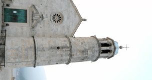 the bell tower of the Church of the Madonna on the Reef or the Mother of God on the Rock on the island of Gospa od Shkrpela against the city of Perast in the Bay of Kotor in Chornogoria.vertical video
