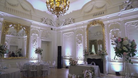 PETERSBURG, RUSSIA - AUGUST, 24, 2021: Served table in a restaurant for dinner, lunch or celebration. White tablecloth, plates, napkins, glasses, chairs. Holiday indoors. Decorated flowers for wedding