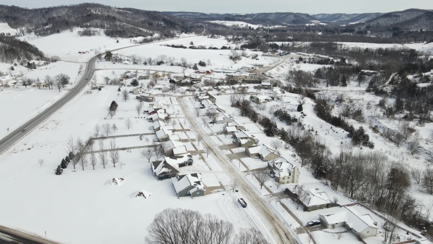 Beautiful landscape view of snow covered valley in Wisconsin. Residential neighborhood nestled in the valley. Rural highway following through the valley to the mountains. 