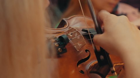Close-up of a beautiful violin played by girl in slow motion. Beautiful young woman, man musician playing the violin. orchestra rehearsal. violinist plays violin at orchestra rehearsal