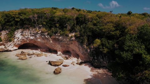 Remote sea caves on secluded beach in the Caribbean; drone over ocean