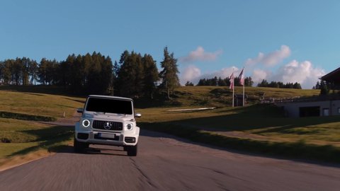 Alpe di Siusi, Dolomites-09.10.2021: Cinematic rolling shot of Mercedes Benz G Class SUV luxury sport car driving on a mountain highway in Alpe di Siusi, Dolomites Mountain Alps, Italy 