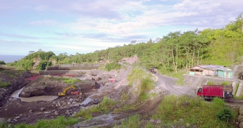 Drone shot of Sand carrying truck passing through the sand mining area. There is an excavator loading the sand into the truck. The name of the location is "Bego Pendem" on the slopes of Mount Merapi