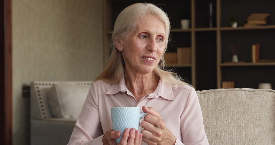 Close up caring adult son comes to older mom sit on sofa with cup, covering her with knitted warm scarf or plaid, cuddling express care, love, showing protection. Multigenerational family bond concept Royalty-Free Stock Footage #1085745368