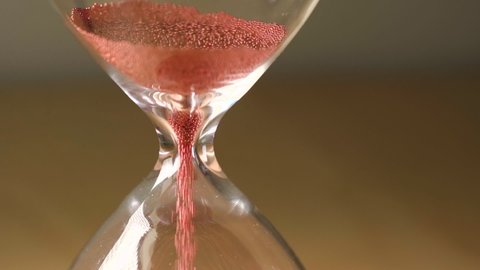 Hourglass measuring the passing time in a countdown to a deadline.
