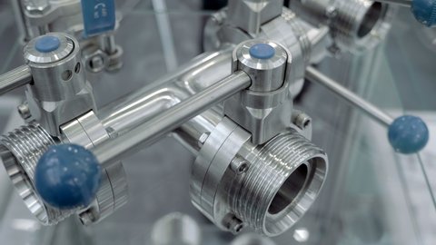 Modern stainless steel industrial ball valves with blue lever used in the food industry. Shot in motion. Closeup
