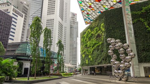 SINGAPORE - CIRCA JAN 2020: Skyscrapers around Raffles Place in Singapore Financial Centre timelapse hyperlapse. Green lawn. People walking around