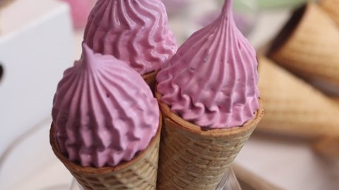 A woman makes marshmallows in waffle cones. With a pastry bag. Wafer cones smeared with chocolate from the inside. Close-up