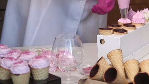 A woman makes marshmallows in waffle cones. With a pastry bag. Horns smeared with chocolate from the inside.