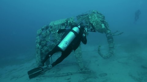 Underwater videographers shooting a sculpture of an elephant on the seabed. Lighthouse dive site, Red Sea, Dahab, Egypt. 4K-60fps