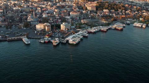 Ferry Boats At Terminal With A View Of Iconic Landmarks - New Mosque And Suleymaniye Mosque In Eminonu, Istanbul, Turkey. - aerial tilt up