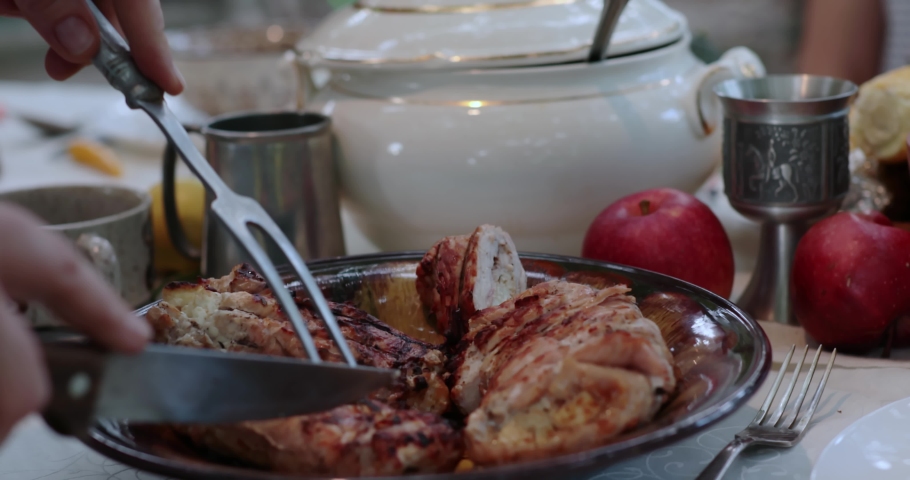 POV hands serve and cut stuffed turkey roll using knife and two prong fork on Thanksgiving dinner table with vintage crockery. Traditional Thanksgiving turkey roulade roasted on grill. Serving dinner