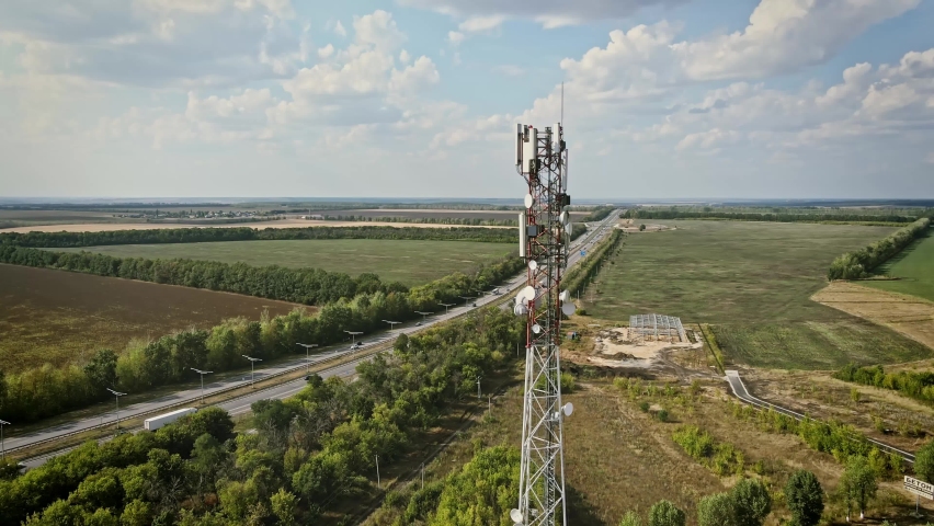 Telecommunication tower 5G near highway with car traffic. Telecom tower antenna and satellite transmits the signals of cellular 5g and 4g mobile signals | Shutterstock HD Video #1085760464