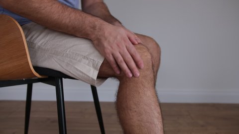 Caucasian Male Putting on Elastic Knee Stabilizer Band to Recover from Injury