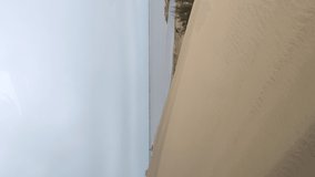 Vertical video. Car driving sand dunes. Dune driving in desert. Indoors white SUV auto off road travel in Africa or UAE. Cloudy day. Summer vacation, trip safari.