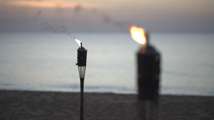 Gas light bamboo torch decorative on sandy beach. Oil lantern burning on beach during sunset.  | Shutterstock HD Video #1085774111