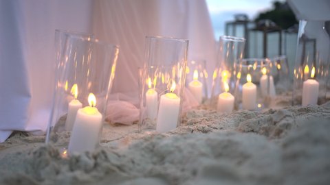 Candlelight bright decoration on sandy beach during sunset. Romantic setting table dinner. Sunset beach dinner table wedding anniversary Muslim , Jewish, Hindu ,catholic 2022.