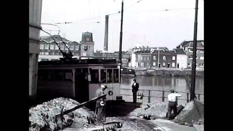 Ghent, Belgium, 1967 - Two unskilled workers suspend work for the passage of the tram