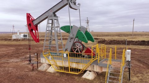 Pump jack in vast oil fields in Russia. Pipelines transporting oil from oil pumps, aerial drone shot