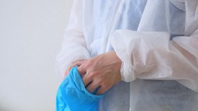 Close-up of putting on surgical gloves. A medical worker in a disposable washing gown puts on blue latex gloves to work in an infected area or before a surgical intervention. Caronovirus. - Powered by Shutterstock - Get 15% off with code: PIKWIZARD15