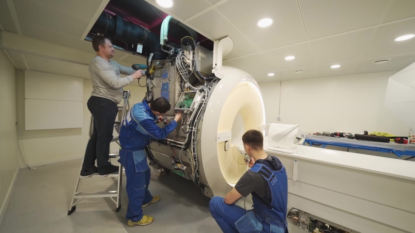 three installer engineers of the magnetic resonance imaging apparatus configure the scanner. professional services. sale and service of medical equipment. Royalty-Free Stock Footage #1085780084