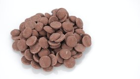 Milk chocolate chips on white background, rotation. Chocolate chips. Confectionery concept. 4K UHD video