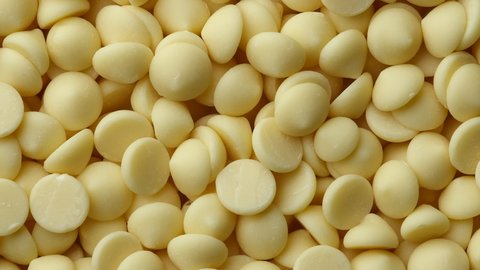 White chocolate chips top view rotation. Camera moves away from the object. Confectionery concept. 4K UHD video