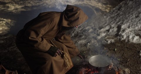 Elderly sorcerer preparing potion in cave