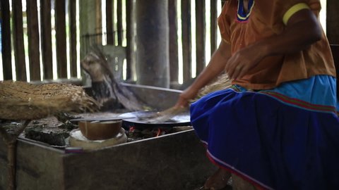 Indigenous wooden kitchen, a woman of the siona culture is cleaning a clay pan to make bread from yuca