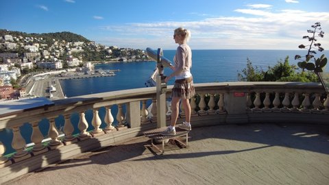 Smiling woman looking Nice from panoramic view of the Nice city and Port Lympia in Blue Coast of France. Aerial view of cityscape with lighthouse from panoramic terrace of Colline du Chateau park.