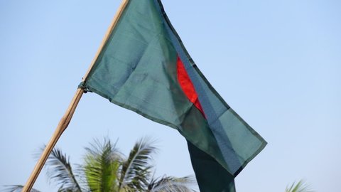 The national flag of Bangladesh is flying in the sky. The flag of Bangladesh is made of a center red circle in green. Close Up View of the national flag of Bangladesh made of Silk fabric. Slow motion.