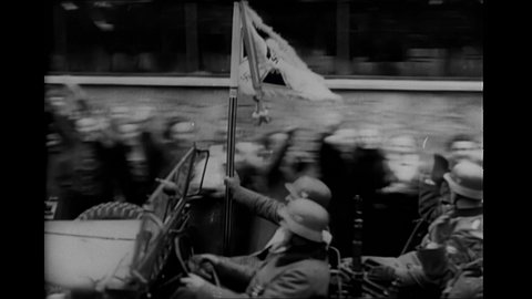 1940s: Mussolini waves to crowd of cheering civilians in street. German soldiers drive car past cheering civilians in streets.