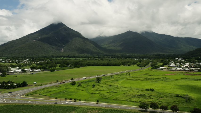 Aerial shot showing traffic on rural Australian road with vegetated mountains in background