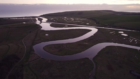 Aerial shot of a meandering river reflecting the sunset at dusk