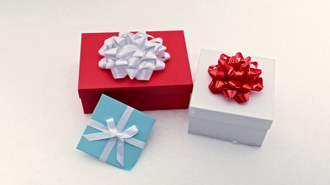 Top view on three bright colorful gift boxes in red, teal blue and white colors, with elegant large white and red bows and white ribbon. Birthday Christmas Anniversary Holiday concept. RED camera shot