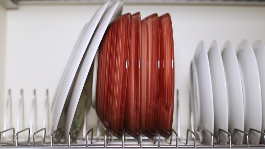 A set of dishes is dried and placed on a metal stand in the kitchen cabinet