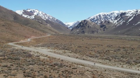 Aerial view of a car on the road with the snowy mountains, in Mendoza.