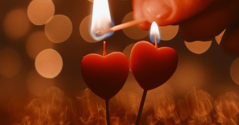 two candles in the shape of a heart burn on a background of beautiful bokeh. valentine's day celebration concept. love two loving hearts