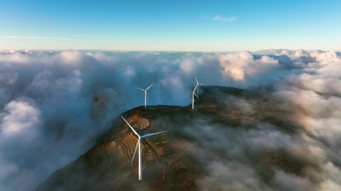 Green alternative wind energy. Renewable energy landscape. Wind turbines produce electricity in the mountains. Wind turbines hidden in the morning fog. Madeira, Portugal. Foggy mystic landscape.
