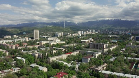Almaty, Kazakhstan - May 6, 2020: Aerial panoramic view of beautiful summer Almaty city at bright sunny day. City center with mountains in the background.